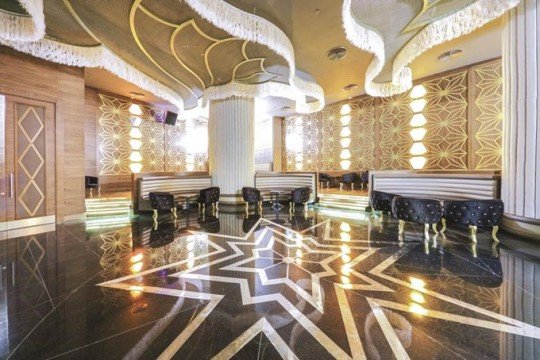 This picture shows a group of people in the middle of a protest. There is a woman at the front of the crowd who is holding a sign that reads "Stop Corruption Now". The other protesters are holding signs as well and chanting. The scene appears to be taking place outside of a large building.