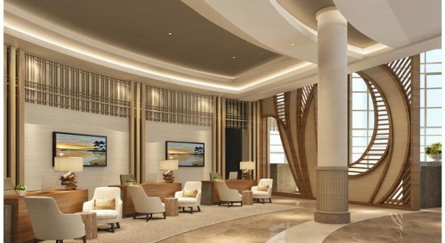 This picture is showing a man with a beard and glasses, wearing a red jacket on a beach. He is standing in front of the ocean, looking out at the horizon.