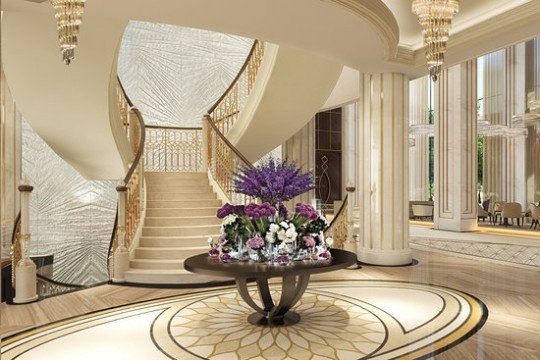 In this picture, there is a beach shoreline with a body of water in the background. The beach is covered in sand with a few rocks and vegetation scattered about. The sky is partly cloudy, with blue and white hues.