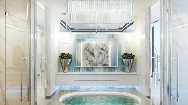 This picture shows a large body of water surrounded by trees and hills. A few sailboats are in the middle of the water and large rock formations can be seen in the foreground. In the background, there is a faint mountain range on the horizon.