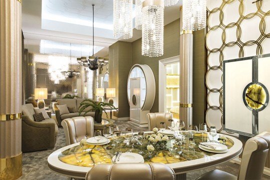 This picture shows an illustration of a one-story brick house, with a green roof and white trim. There is a chimney at one corner of the roof, and a window on either side. There is a light yellow door in the center of the house, and a path leading up to it.