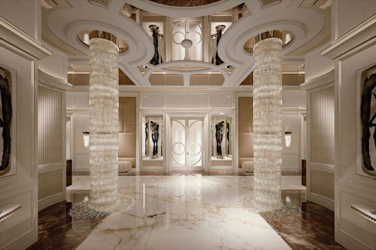 This picture appears to show a person, viewed from behind, though the face is hidden in shadow and cannot be seen. The person is wearing a navy blue bomber jacket, with the sleeves rolled up slightly, and has their arms outstretched, palms facing down. The sky above them is bright orange, likely indicating an early evening or sunset.