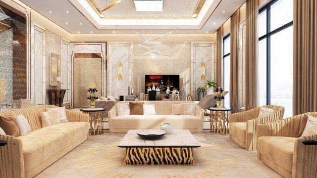 This is a picture of a modern dining room designed by Antonovich Design. The room features a large, round glass-top dining table with black chairs, surrounded by a beige and white geometric wallpaper. There is a black and silver chandelier hanging from the ceiling, and a grey velvet sofa in the corner. To complete the look, there are two ornate silver wall sconces and a white fireplace with a marble surround.