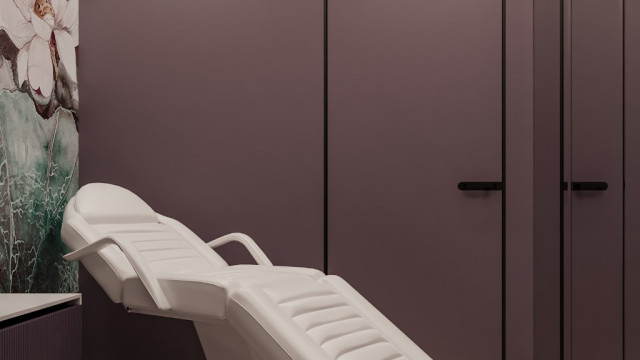 The picture shows a luxurious living room, designed by Antonovich Design. It has beautiful elaborate furniture including a large comfortable sofa with several cushions, two elegant armchairs, and a coffee table. The walls are decorated with ornate wall hangings and paintings in classic gold frames. A white marble fireplace and grand crystal chandelier give the room a luxurious atmosphere.