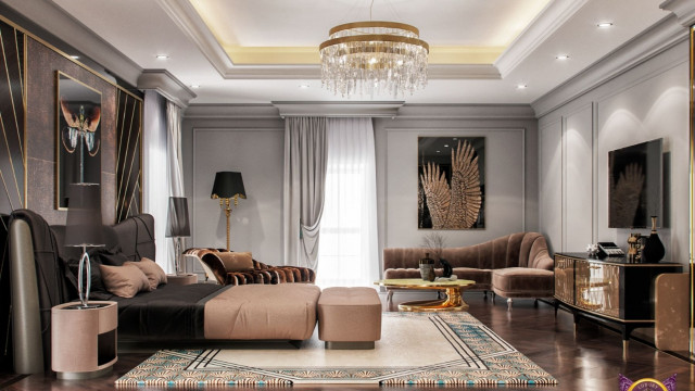This picture is a rendering of a modern, luxurious living room featuring a sectional sofa in a bold blue velvet upholstery with deep tufting and low profile. A large round silver mirror is mounted on the wall opposite the sofa, along with several modern abstract art pieces. The walls are covered in a light beige wallpaper, and the room is illuminated by two classic black and gold lamps sitting atop two small side tables on either side of the sofa.