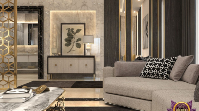 This image shows a modern living room design featuring a stone wall with a fireplace, a comfortable couch, and a large round wooden coffee table. There is also a round-backed armchair and multiple shelves of artwork on the wall. The overall design of the room has an airy feel and natural elements, such as plant life and wood furniture, allow the space to feel organic.