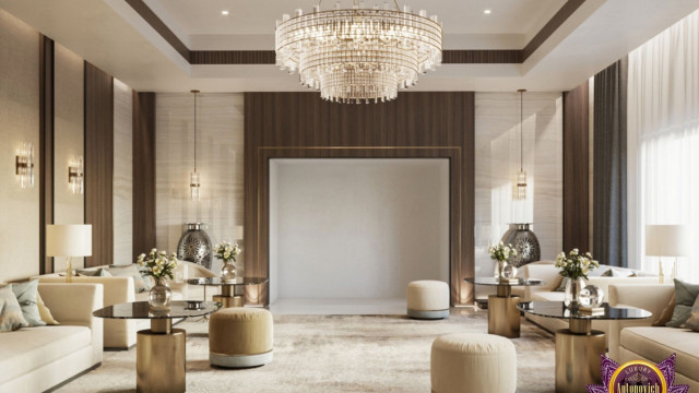 This picture depicts a modern, luxurious bedroom design. The room is decorated with rich, cream-colored walls and gold accents. There is an eye-catching chandelier hanging from the ceiling, as well as a plush tufted sofa with velvet upholstery at the center of the room. A white marble coffee table sits in front of the sofa, framed by multiple low poufs for extra seating. There is also a patterned rug on the floor to tie the whole look together.