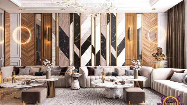 This picture shows a modern, luxury living space designed by Antonovich Design. It features a large, light grey sectional sofa and armchair, facing a striking marble coffee table on a thick white rug. The walls around the furniture are painted in a dark shade of blue with light-colored trim, and accented by an oversized abstract painting and two bronze wall sconces. Behind the furniture is a decorative column and an arched doorway leading to an antechamber.