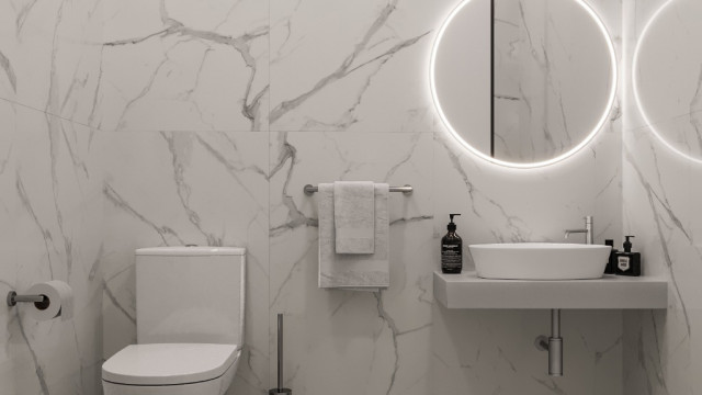 This is a picture of a luxurious modern living room designed by Antonovich Design. The room features a gorgeous ceiling with intricate gold accents, and beautiful recessed lighting. A stylish grey sofa sits in the center of the space with black and white patterned furniture pieces scattered around it. The walls are decorated with large abstract art pieces and an area rug completes the look.