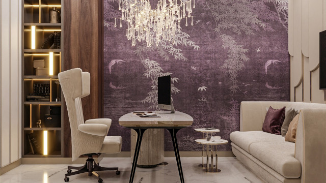 The picture shows a luxurious and modern-style living room with a taupe sofa, cushioned armchairs, ottomans and coffee table. The walls are painted in a light gray color, and there is a large contemporary fireplace with a black marble surround and wood mantel. A round, white chandelier hangs above the coffee table, and there are various plants and artwork throughout the space.