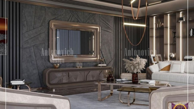 This picture shows a luxurious white and gold bedroom with ornate details. It features a white headboard, bed frame, and night stands with golden accents. A white chandelier hangs above the bed, and there is a large mirror with a golden frame on the wall. The walls are painted in a pale green color, and the floor has a cream-colored rug.