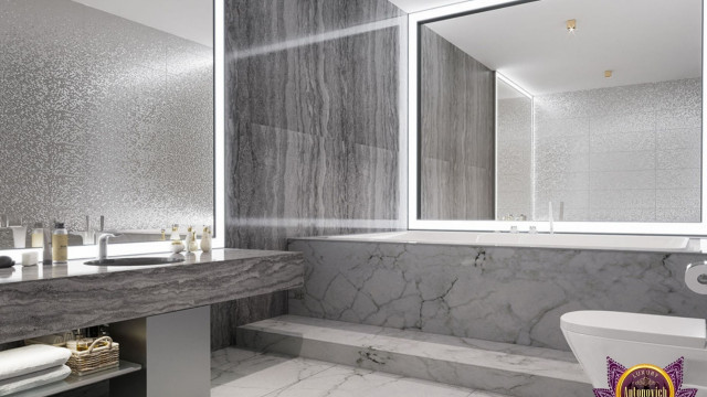 This picture shows a luxurious modern bathroom featuring a large, white soaking tub with gold-toned fixtures and taps. The walls are a light beige with a hint of marble, complemented by a black-and-white tiled floor. The vanity features a large sink and countertop with a built-in storage drawer and large mirror above it. The room is illuminated by multiple recessed lighting fixtures. The overall look is one of elegant sophistication.
