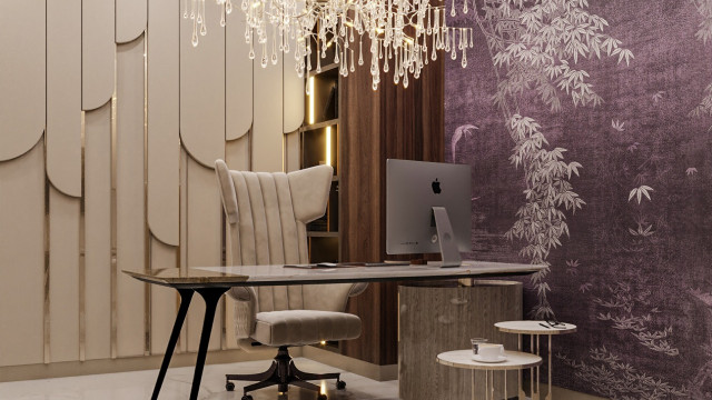 This picture shows a luxurious modern living room. The space features a dark grey sectional sofa and two white armchairs, arranged around an ornate white coffee table with a glass top. The walls are painted a warm beige color, while the flooring is light wooden. A large statement painting hangs on the wall, providing a striking visual contrast to the furniture. The room also includes a built-in fireplace, as well as plenty of plants for added warmth and vibrancy.