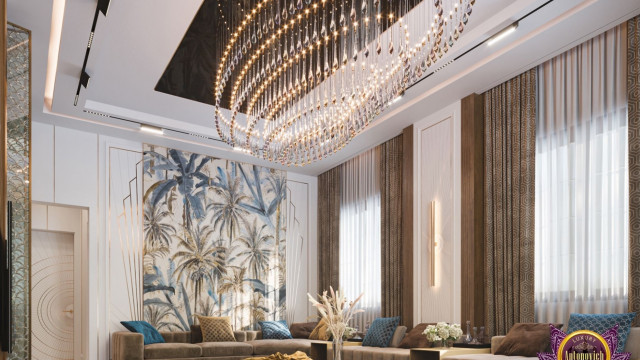 Modern, luxurious living room with white and light beige walls, white ceiling, round shaped light fixture, large sectional sofa upholstered in light beige fabric, two end tables with tall lamps, and brown and gold area rug.