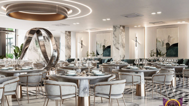 This picture shows an interior design of a modern bedroom. It appears to be a contemporary and luxurious space with its hardwood floors, high ceilings, and white walls that contrast with the dark furniture and bold accessories. The focal point of the room is the statement bed which is encased in a beautiful canopy and accompanied by a tufted chaise lounge. On either side of the bed are distressed nightstands, adding to the decor. Discreet lighting fixtures complete the look of the space.