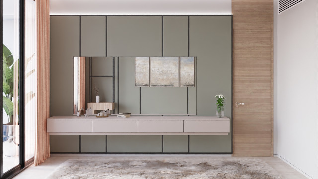 This picture shows a modern living room in shades of white, black and grey. The space is luxurious and features a sofa with patterned cushions and a grey shag rug. To the side there is a round black table with a shiny gold lamp on top. On the other side there is an elegantly designed shelf with items of decor, including a modern vase and a geometric sculpture.