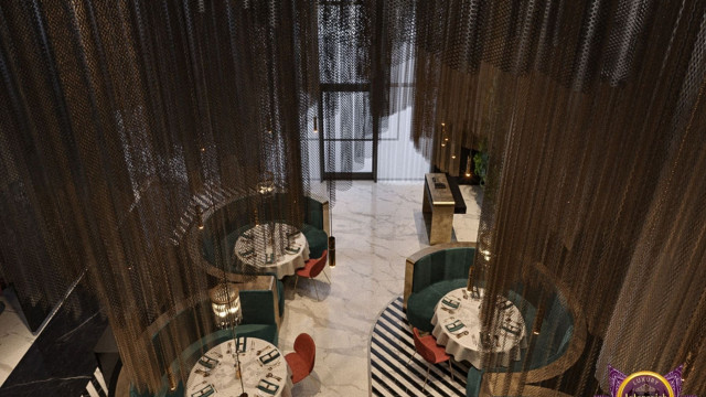 This picture shows a luxurious kitchen designed by Antonovich Design. It has an island in the center with a marble countertop, marble backsplash, and custom cabinets. The kitchen also features a built-in refrigerator and freezer, a stove, and an oven. There are bronze pendant lights hanging from the ceiling and accent pieces scattered throughout the room. The floor is tiled with a geometric pattern that adds a unique design element to the space.