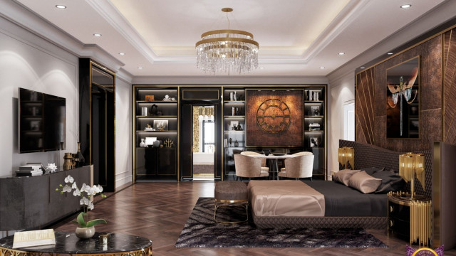 This picture shows a luxurious dining room with a contemporary design. The room features an elaborate chandelier and a large gold mirror hung on the wall. There is a wooden dining table surrounded by red velvet dining chairs, and a buffet cabinet with glass doors. The walls are grey and white, and there is a patterned area rug in the center of the room.