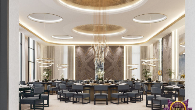 This picture shows a luxury living room with a dark brown and white color scheme. The room has a seating area with a white sofa and two armchairs upholstered in chocolate-colored velvet. On the other side of the room, there is a wall with built-in shelving and a flat screen TV mounted on it. The floors are covered in parquet wood in a herringbone pattern. The walls have large built-in window frames and several wall lamps with intricate golden details. A small glass round table with a golden base is placed in one corner with a statement rug