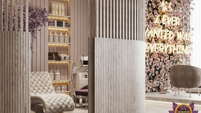 This picture shows a modern, luxurious living room with a large, light-colored sectional sofa along the wall. The walls are decorated with dark wood paneling and abstract canvases. There is an abstract area rug in front of the sofa and a round glass coffee table in the center of the room. The room also has floor-to-ceiling windows and crystal chandeliers that give it a glamorous feel.