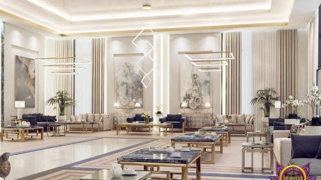 Modern interior featuring white-walled space filled with expensive furniture, including a large gray chaise lounge, glass-top table, and white sofa with decorative patterned pillows.