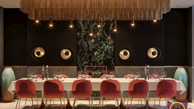 This picture shows a luxurious living room, draped in white and gold accents. A large, light-filled window offers views of a lush backyard, while an elegant sofa and chairs sit around a glass coffee table, providing comfortable seating and plenty of room to entertain. On the walls, a combination of abstract art and mirrors add a unique touch of style to the room. The floor is adorned with a stunning patterned rug, creating a warm and inviting atmosphere.