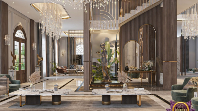 This image is of a modern luxury living room designed by Antonovich Design. It features a white and gray color palette with pops of blue. The space includes two accent chairs, a sofa, a low coffee table, and a low stone-topped end table. There are two lamps on the end tables and a black floor lamp beside the sofa. The walls feature artwork and a mirror, and the ceiling has recessed lighting.