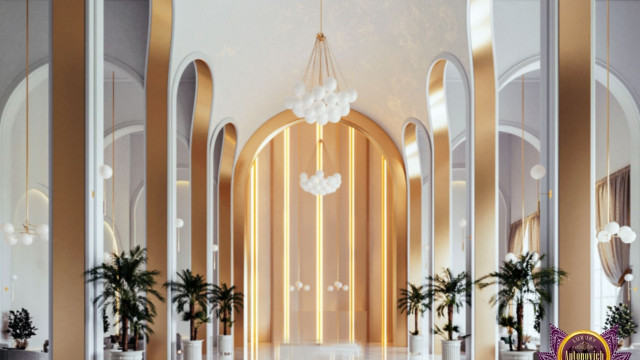 This picture shows a luxurious interior design in a modern home. The room features a white and grey color scheme, with a marble flooring and a large glass window on the wall that overlooks the city skyline. The walls are adorned with beautiful artwork, and the furniture is made of a combination of leather, velvet and wood. There is also an ornate chandelier that hangs from the ceiling, giving the space a warm and inviting atmosphere.