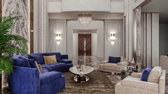 This picture shows an elegantly designed, modern living room with luxurious touches throughout. The space has an off-white hue on the walls with a recessed ceiling, which is framed by intricate crown molding. Large windows let in plenty of natural light, while the floor is covered in a beautiful parquet patterned hardwood. The furniture includes an upholstered sofa and matching armchairs, and the overall look is finished off with a crystal chandelier and eye-catching wall art.