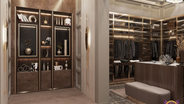 This picture shows a modern living room with a white minimalist design. There are two plush gray couches along the walls, separated by a small glass coffee table in the center of the room. The walls are painted white and there is an abstract painting on the wall. The floor is carpeted in gray and there is a modern pendant lamp hanging from the ceiling. The overall look of the space is minimalistic and calming.