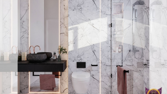 This picture shows a modern, luxurious interior space decorated in shades of beige and brown. The room features several comfortable seating options, including a sleek beige leather couch, two armchairs, and two ottomans. A large, eye-catching crystal chandelier hangs from the ceiling, and the walls are adorned with abstract art pieces. An ornate glass coffee table sits in the center of the room, complete with a large flower vase and books.