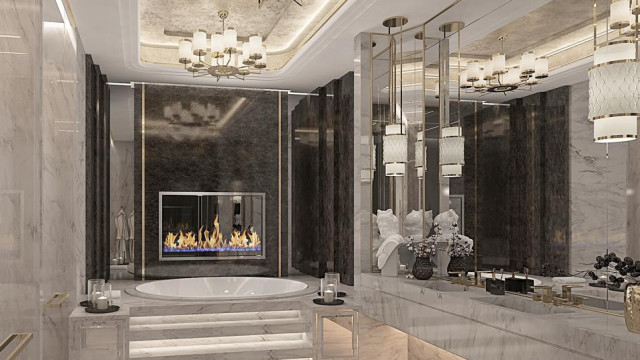 This picture shows a luxury, modern apartment. It features a sleek, white kitchen with granite countertops and stainless steel appliances. There are dark hardwood floors and neutral-colored walls. The living room has an elegant cream sofa, an ornate coffee table, and a stately stone fireplace. There is also a large window that overlooks the city skyline.