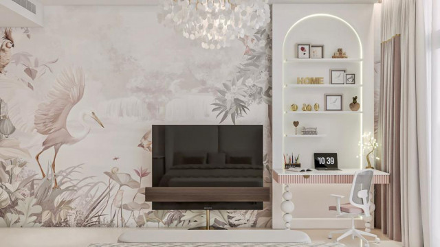 This picture shows an artistically designed modern contemporary living room with large floor-to-ceiling windows overlooking a stunning city skyline. The space features a large L-shaped sofa with colorful geometric cushions, a white fireplace with a built-in entertainment center, and a sleek black coffee table. The walls are painted white with subtle blue and grey patterned wallpaper accenting the area. Geometric shelving units flank either side of the fireplace, and a glass chandelier adds the perfect finishing touch.