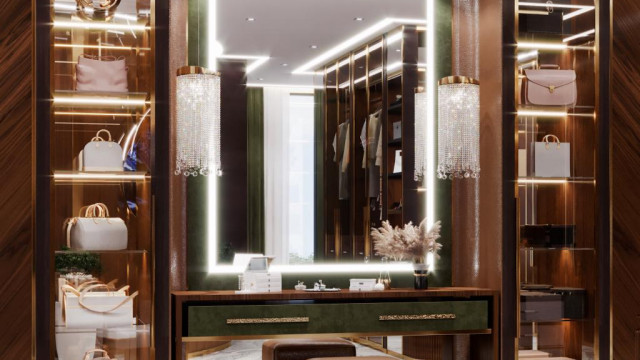 This picture shows a contemporary living room in an elegant home that features modern style furniture and décor. The room is decorated in shades of grey and white, with a large abstract painting on the wall. There is a white sectional sofa, as well as a grey armchair and ottoman, both of which feature angular lines and geometric shapes. The walls and ceiling have built-in lighting, and there is a white fur rug and a glass coffee table in the center.