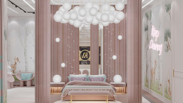 This picture shows a luxurious contemporary living room with a grand white sofa situated in the center against a light gray wall. The sofa is surrounded by an array of throw pillows, accent chairs, and a circular ottoman. Above the sofa hangs an ornate chandelier, and surrounding it are modern art pieces and decorations. The floor is finished in a rich dark wood that contrasts beautifully with the light walls and furnishings.