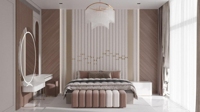 This picture shows a luxurious modern living room. It features a gold rug, two velvet beige sofas, one black leather armchair, and several patterned throw pillows. On the wall there is a large painting depicting an outdoor scene with a mountain range in the background. The room also includes two floor lamps, a glass coffee table, and a chandelier hanging from the ceiling.