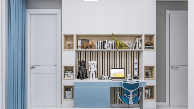 The picture shows a modern, luxurious living room with a white marble fireplace, surrounded by abstract artwork, and simple furniture upholstered in gray velvet. The walls are painted a creamy white, while the ceiling is adorned with intricate moldings. The room is illuminated by both natural light coming in through the large wall-to-wall windows and modern lighting fixtures.