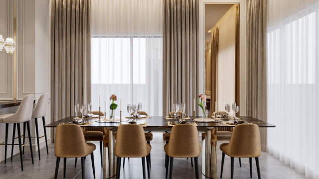 A grand entrance foyer with a detailed ceiling, marble flooring, luxuriously furnished seating area, and a statement chandelier.