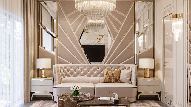 This picture appears to be a luxury bedroom designed by Antonovich Design. The room has a muted grey and white color palette, featuring an ornate bed with dark wood trim. On either side of the bed are two matching nightstands, with detailed designs on the drawers. In the background, there is a large window with thick velvet curtains, as well as a luxurious armchair in the corner of the room.