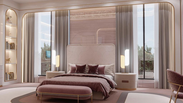 The image shows a luxurious modern home. There is a grand entryway with a beautiful large door flanked by two tall columns. The ceiling is decorated with intricate carvings and designs, and there are several crystal chandeliers hanging from it. The walls are adorned with decorative art and the floor is made of gleaming marble. The staircase is made of a glossy dark wood and appears to be winding up to the second floor. On either side of the staircase are two large windows that offer views of the home's lush yard and surrounding landscape.