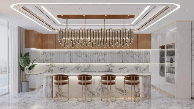 This picture shows a modern kitchen design featuring a large island and countertops made of white quartz, illuminated with white LED lighting. The cabinets are in a two-tone color with the lower units in a bright teal shade and the upper units in white. A kitchen range is located on the Island surrounded by stylish bar stools. The island has ample storage space, deep drawers, and wine racks. The floors are covered in checkered tile which adds a stylish contrast to the overall design.