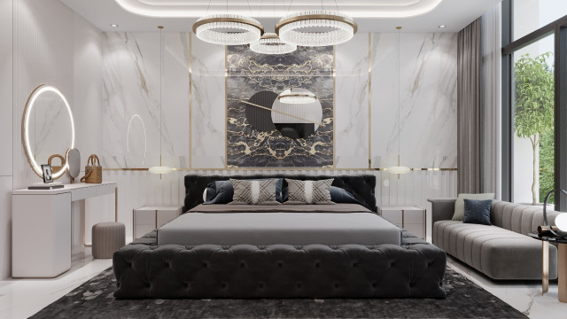 This image shows a modern living room with luxurious furniture, art, and decor. The main focus of the photo is the beige sofa in the center, which is surrounded by accent chairs in warm colors and a unique patterned rug. There are also several pieces of artwork on the walls and a round gold chandelier that adds a glamorous touch.