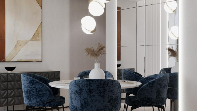 This picture shows a luxurious living room designed by Antonovich Design. The room features a grand marble staircase, a grey velvet sofa set, a large chandelier and multiple gold accents. The floor is a marble pattern and the walls are elaborately decorated with gold accents and wall paintings. The furniture looks plush and comfortable for a perfect living experience.