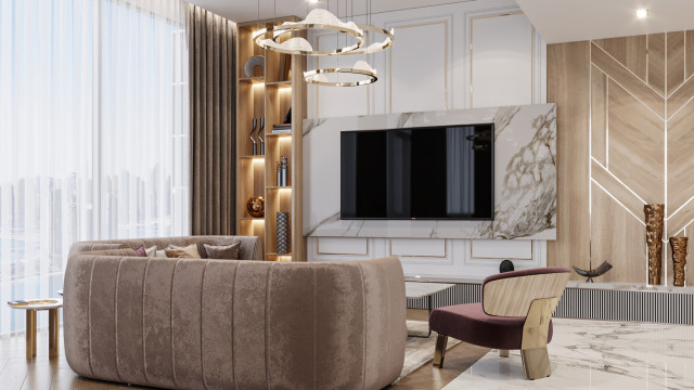 This picture shows a luxurious living room with a grand vaulted ceiling featuring ornate chandeliers and recessed lighting. The walls are decorated with art that is framed in intricate gold, while luxurious furnishings cover the floor. A large area rug in jewel tones adds an extra touch of elegance to the space, and a large fireplace anchors the room.