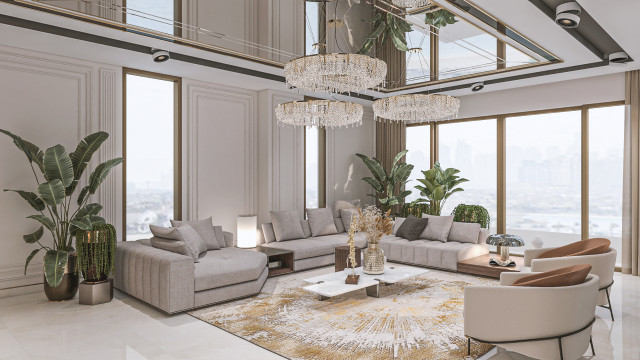 Modern living room interior with white walls, ceiling and light hardwood flooring, grey and blue velvet sofas and ottomans, glass coffee table, artwork on wall, and multiple pendant lights.