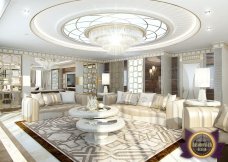 The picture shows two people, a man and a woman, standing on the edge of a coastal cliff overlooking the ocean. They are both wearing sunglasses and the woman is wearing a white hat. The man is holding a small digital camera and they appear to be enjoying the view.